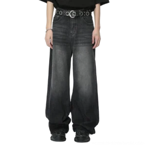 Model wearing charcoal fade wide-leg jeans with a black T-shirt, grommet belt, and black sneakers in a streetwear outfit