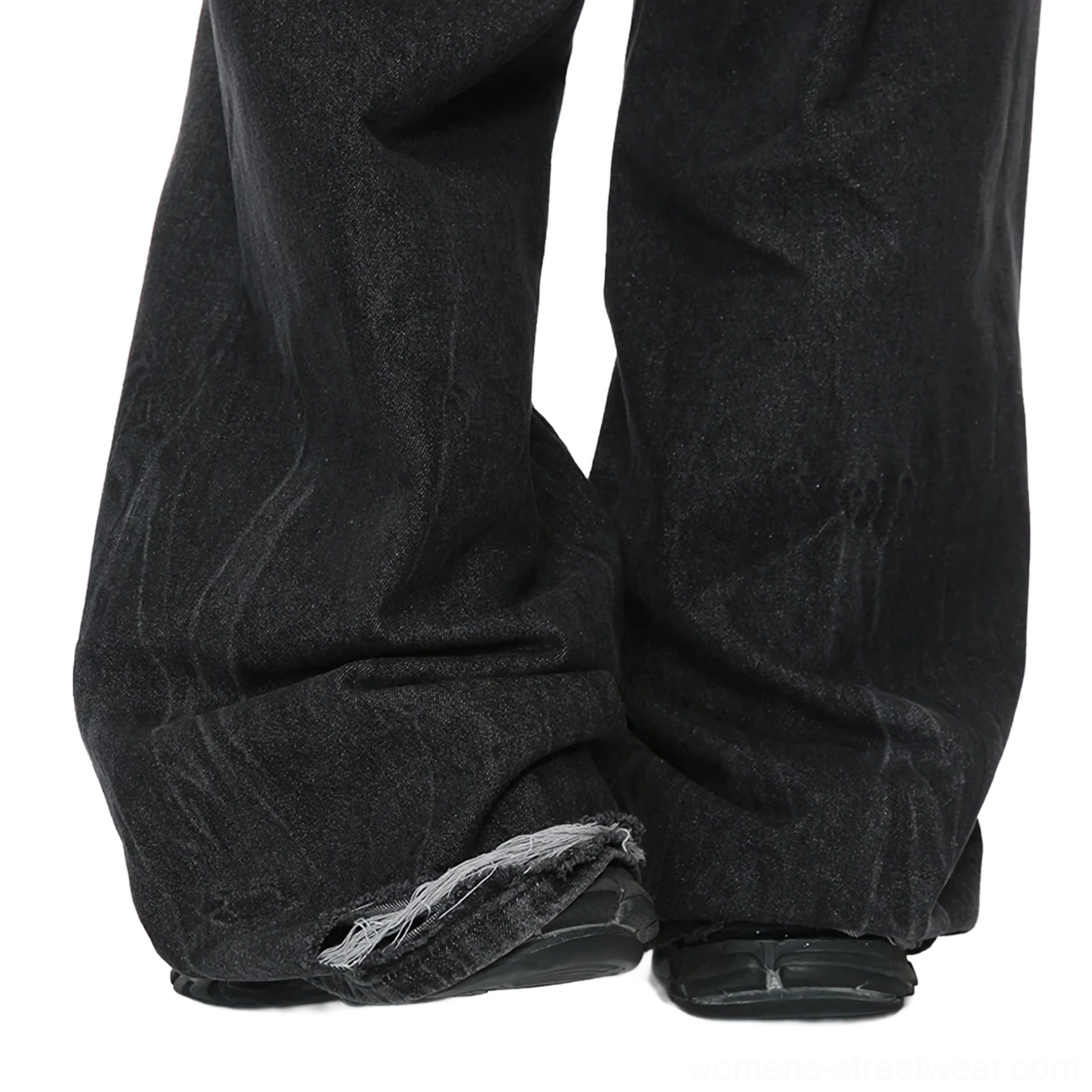 Close-up of charcoal fade wide-leg jeans showing heavy washed denim texture, natural creases, raw frayed hem, and black footwear