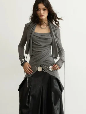 Charcoal gray asymmetric draped layered streetwear top shown from a front three quarter view with cowl neckline twisted wrap front long sleeves and circular chain waist detail