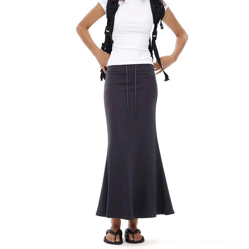 Dark charcoal gray fitted mermaid maxi skirt shown from a back three-quarter view with an adjustable waist and flowing floor-length hem