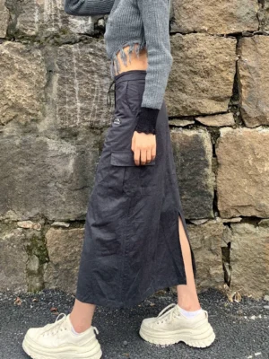 Charcoal gray high-waist drawstring cargo maxi skirt side view with utility pocket and side slit styling