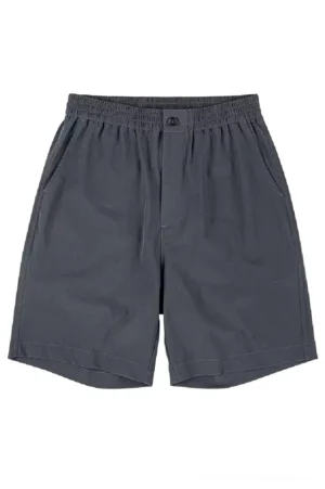 Dark charcoal gray lightweight outdoor tech shorts shown from the front with elastic waistband button closure side slash pockets and relaxed oversized streetwear fit