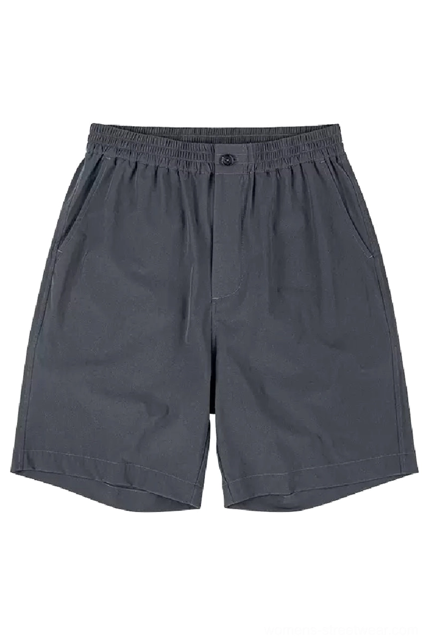 Dark charcoal gray lightweight outdoor tech shorts shown from the front with elastic waistband button closure side slash pockets and relaxed oversized streetwear fit