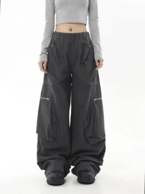 Charcoal gray oversized streetwear cargo pants shown from the front with wide legs, large utility pockets, zip details, and chunky black boots