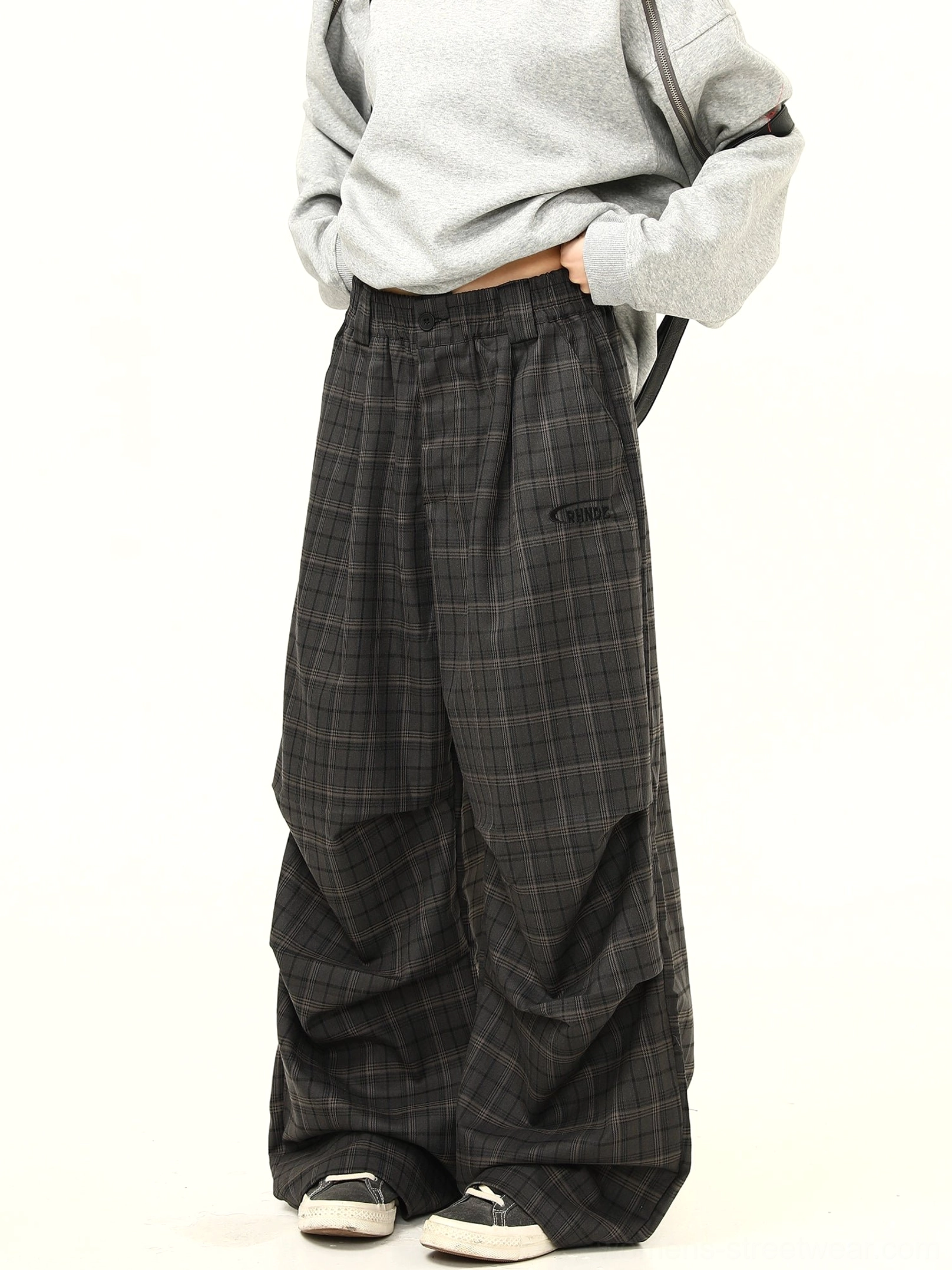 Close-up of charcoal gray checkered streetwear pants showing the waistband subtle plaid fabric and front embroidery detail