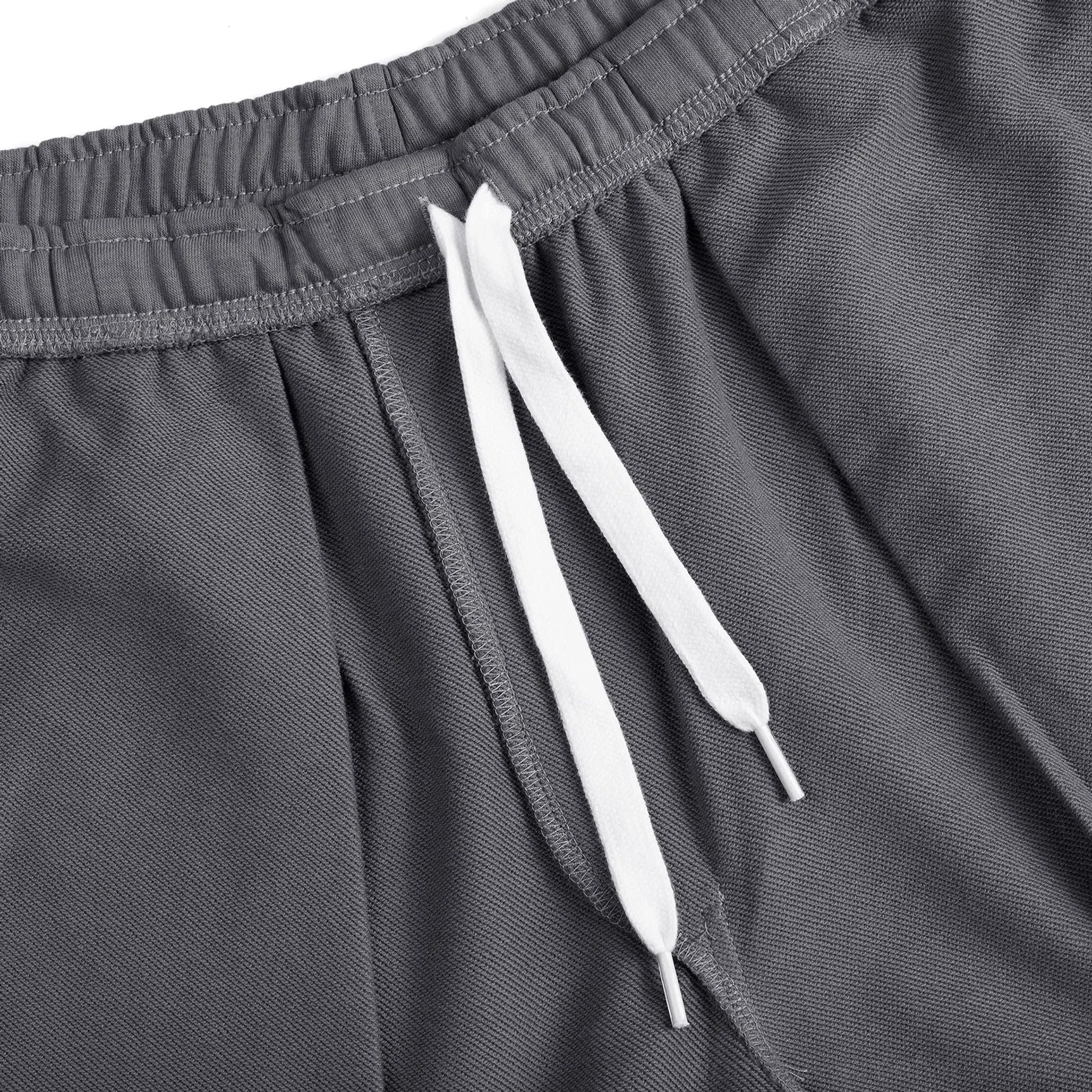 Close-up of charcoal gray relaxed fit shorts showing folded elastic waistband, white drawstrings and soft French terry knit texture