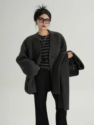 Dark charcoal gray wool jacket with matching scarf detail, relaxed drop shoulder fit, single breasted front, and cropped streetwear silhouette on a female model