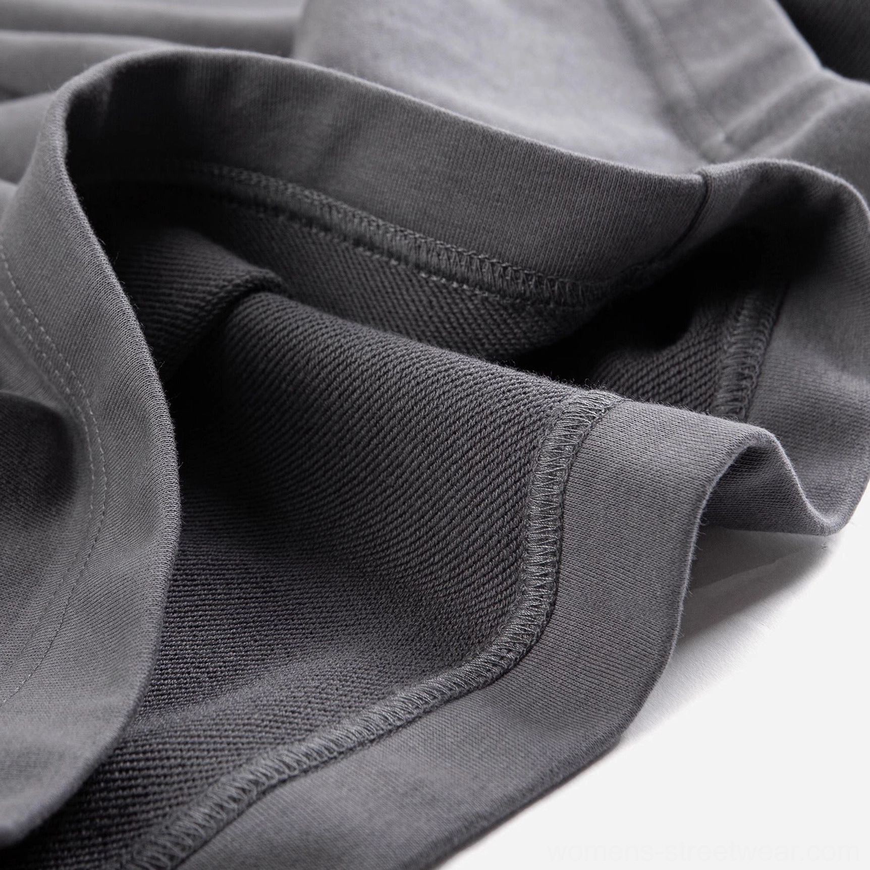 Close-up of charcoal gray streetwear shorts with double-stitched rolled hem and soft draped French terry fabric