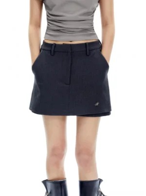 Charcoal gray tailored mini skort front view with fitted waist, front zipper, side pockets, pleat detail, and black boots