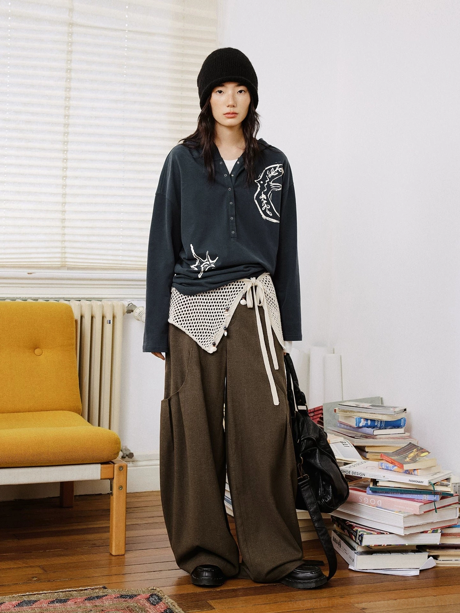 Dark charcoal oversized embroidered graphic Henley polo shirt styled with brown wide-leg trousers and a black beanie