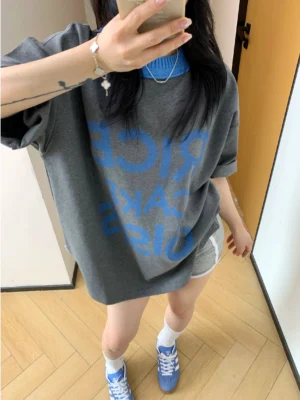 Loose charcoal oversized graphic tee with blue reversed lettering styled with white crew socks and blue retro suede sneakers
