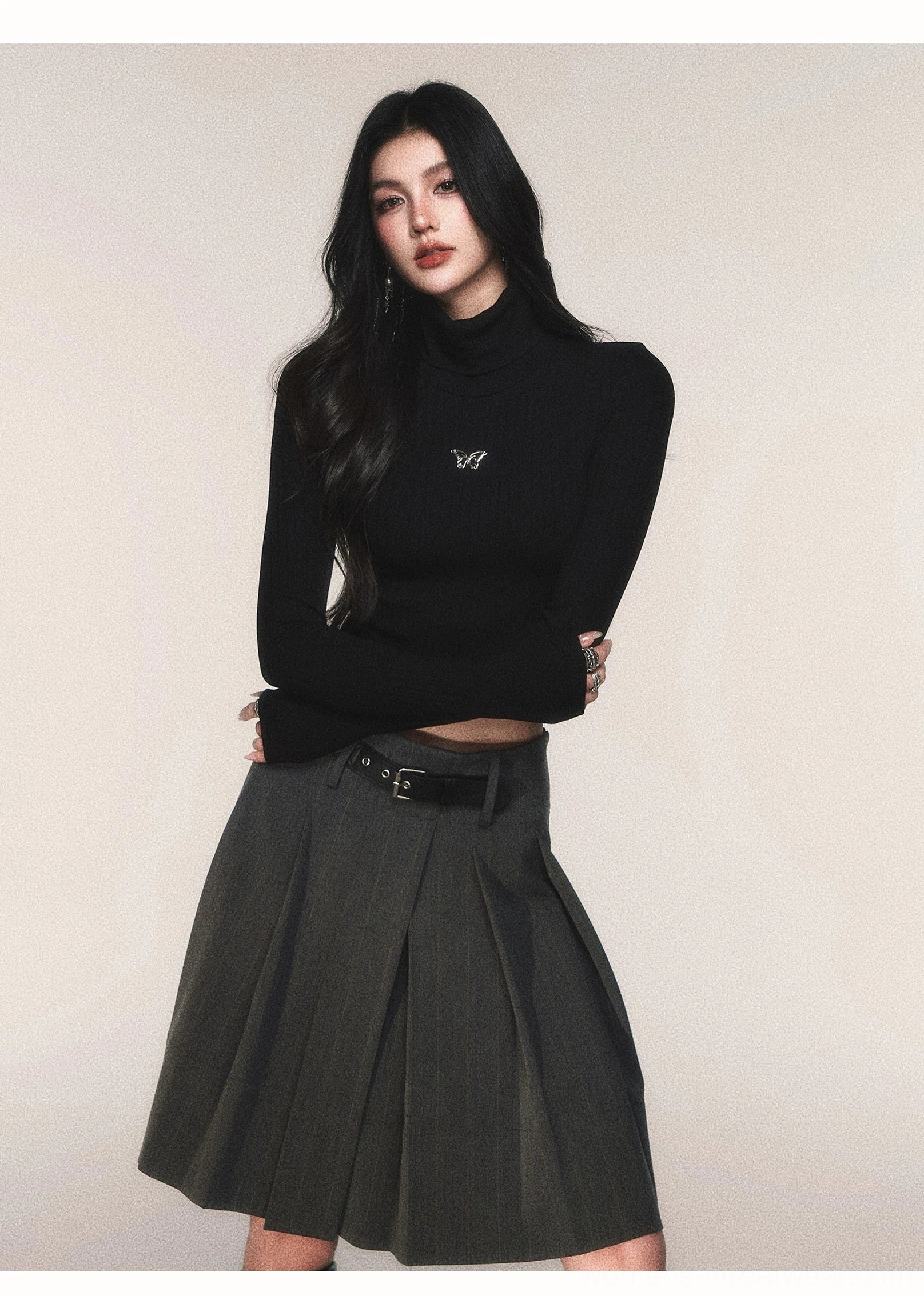Charcoal gray pinstripe pleated midi skirt with black belt styled with cropped black turtleneck and black heeled boots