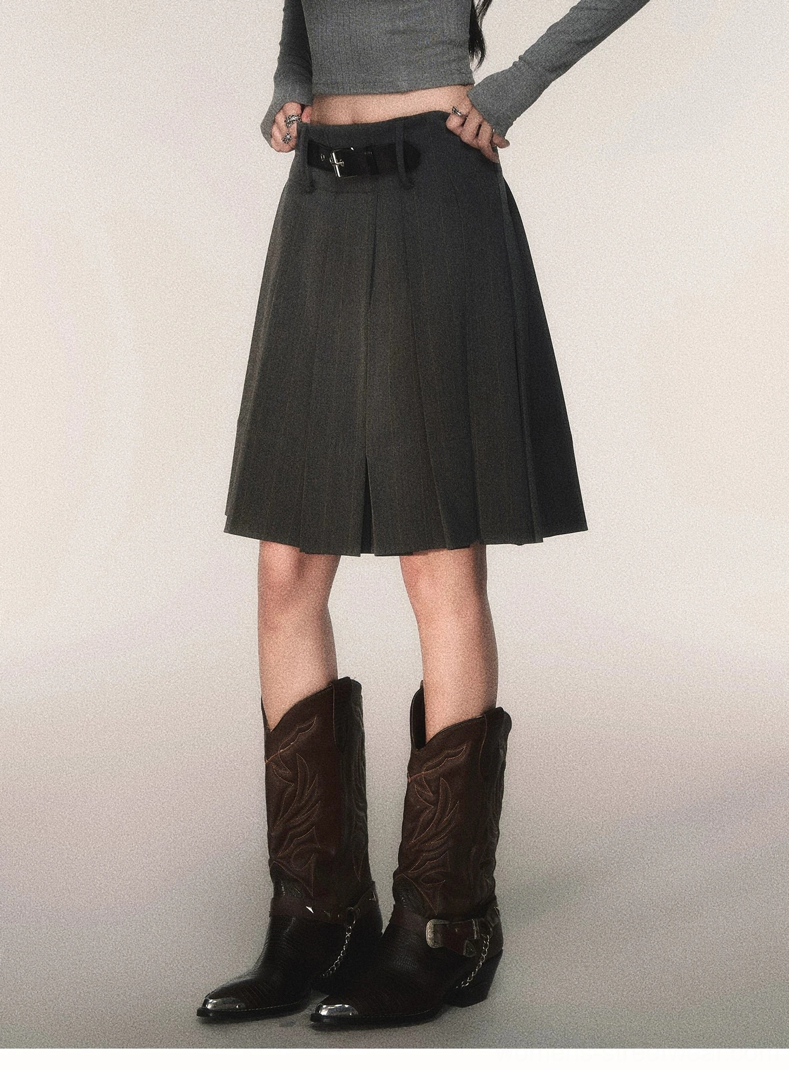 Charcoal gray pinstripe pleated midi skirt with detachable black belt styled with cropped gray top and brown cowboy boots front view