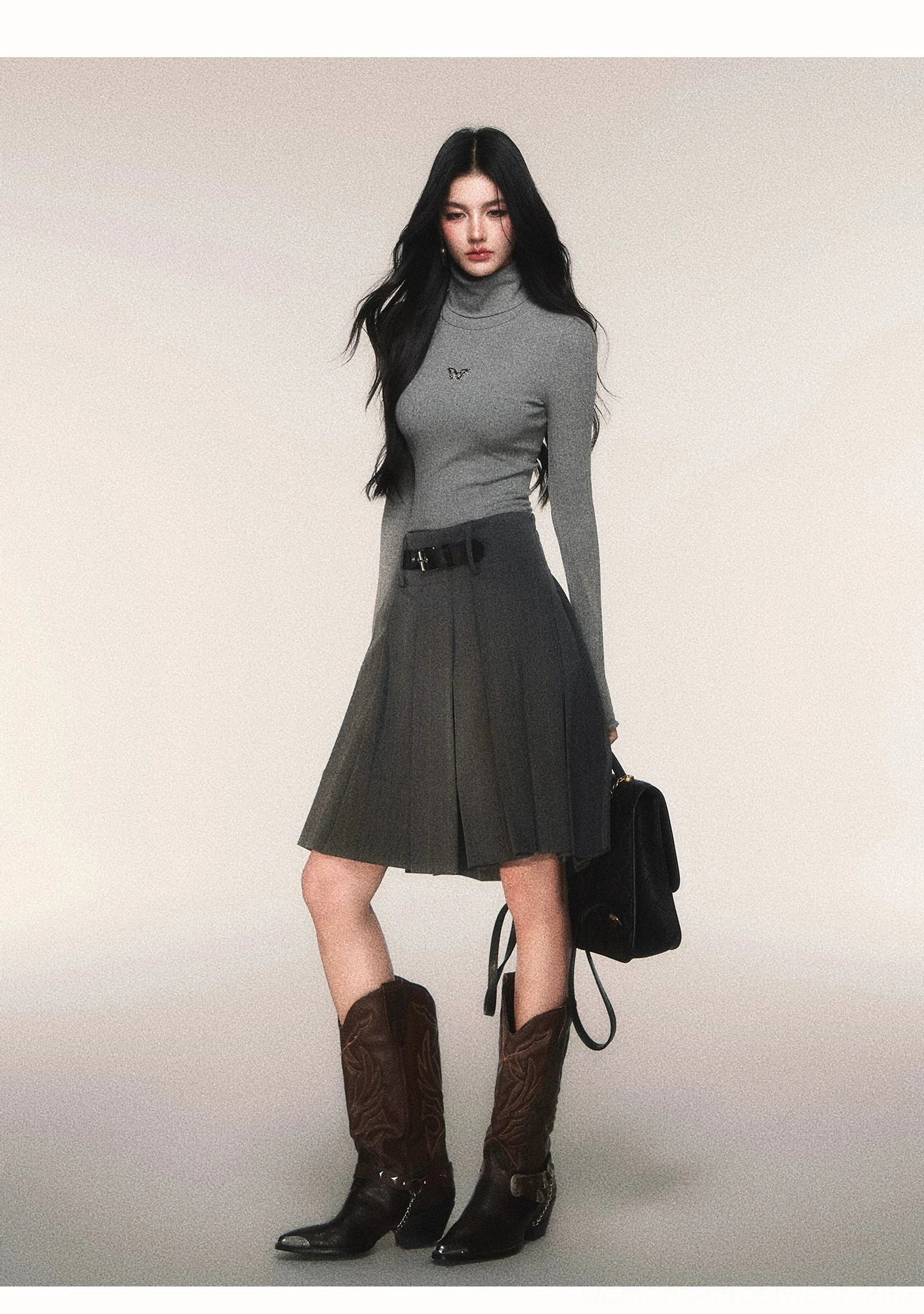 Charcoal pleated midi skirt in pinstripe suiting fabric styled with gray turtleneck black shoulder bag and western boots