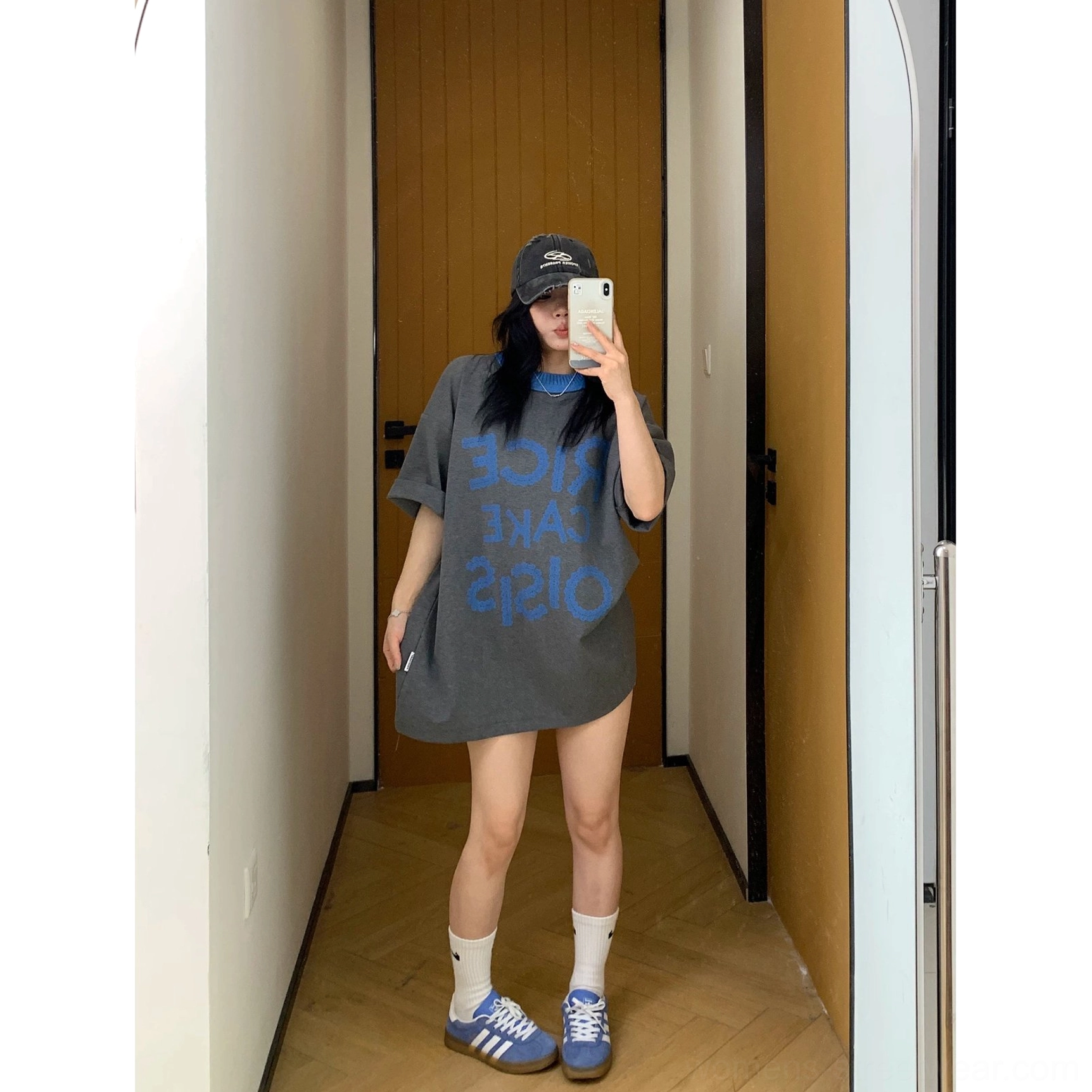 Full-body view of charcoal oversized RICE CAKE 015 graphic tee with blue print, light grey biker shorts, white socks, blue sneakers, and baseball cap
