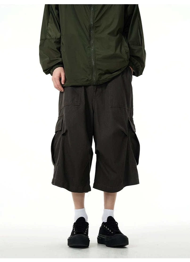 Front view of charcoal wide-leg cargo pants showing button zip fly multiple pockets and relaxed streetwear fit
