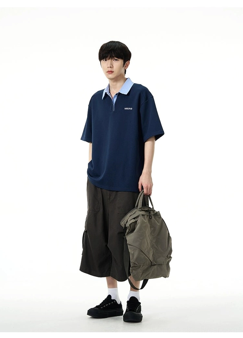 Dark charcoal wide-leg cargo pants styled with a navy polo shirt gray tote bag black socks and streetwear sneakers