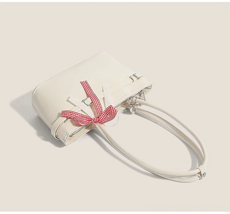 Cherry picnic off-white leather-look shoulder bag shown from the side with gingham bow, silver buckles, and detachable shoulder strap detail
