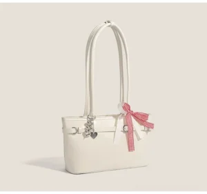Cherry picnic ribbon baguette bag in off-white glossy faux leather with red gingham bow, silver heart charm, and structured underarm shoulder design