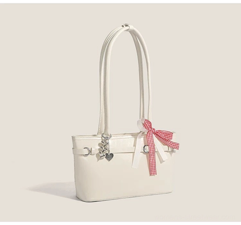 Cherry picnic ribbon baguette bag in off-white glossy faux leather with red gingham bow, silver heart charm, and structured underarm shoulder design