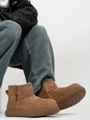 Chestnut brown suede shearling ankle boots worn with blue jeans and a black quilted jacket, showing the chunky non-slip platform outsole