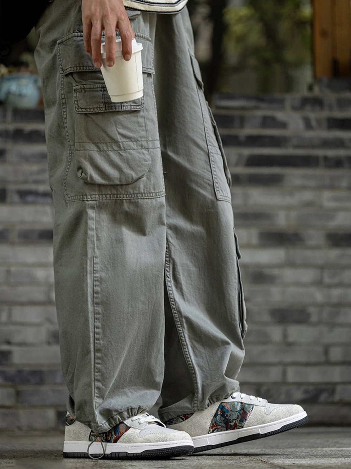 Chinese embroidered bird brocade court sneakers worn with olive cargo pants beside a brick wall in an urban streetwear setting