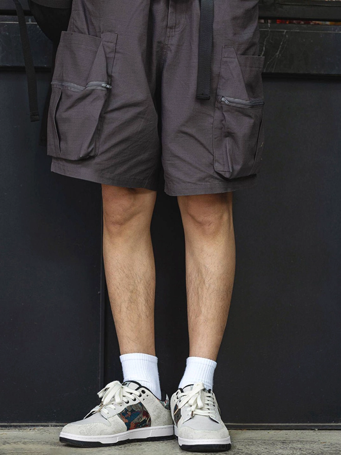 Front low-angle view of white Chinese embroidered bird brocade court sneakers styled with crew socks and cargo shorts