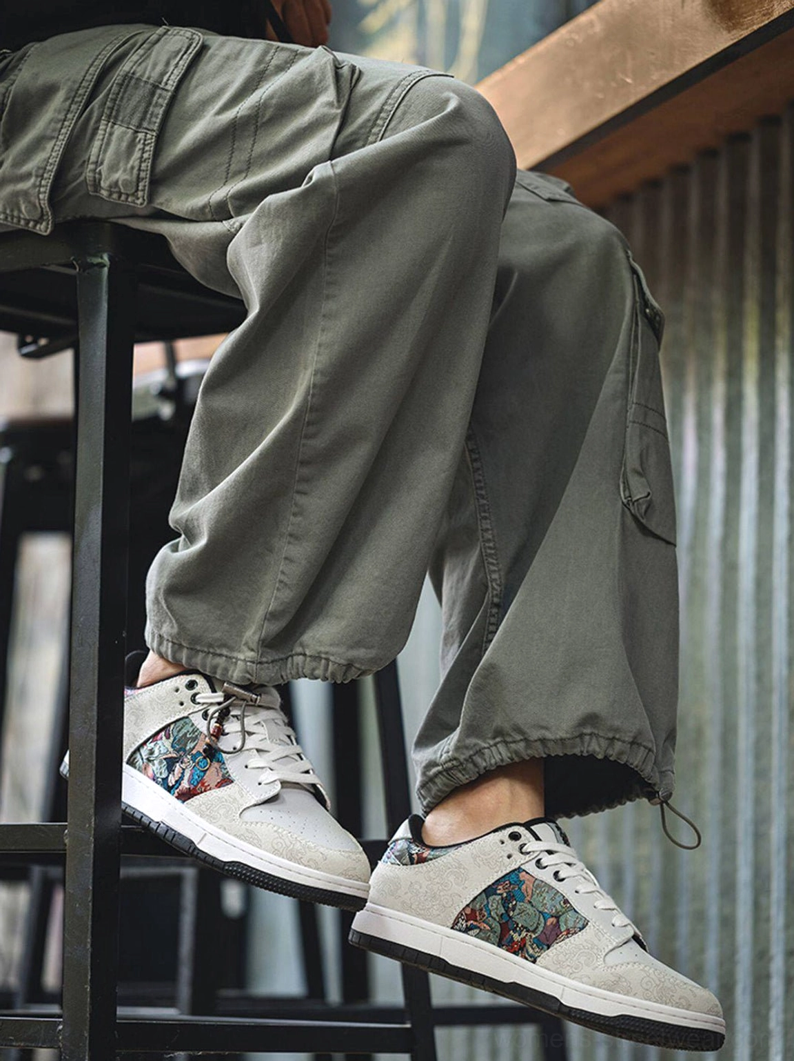 White Chinese embroidered bird brocade streetwear court sneakers worn with olive cargo pants in an industrial urban setting