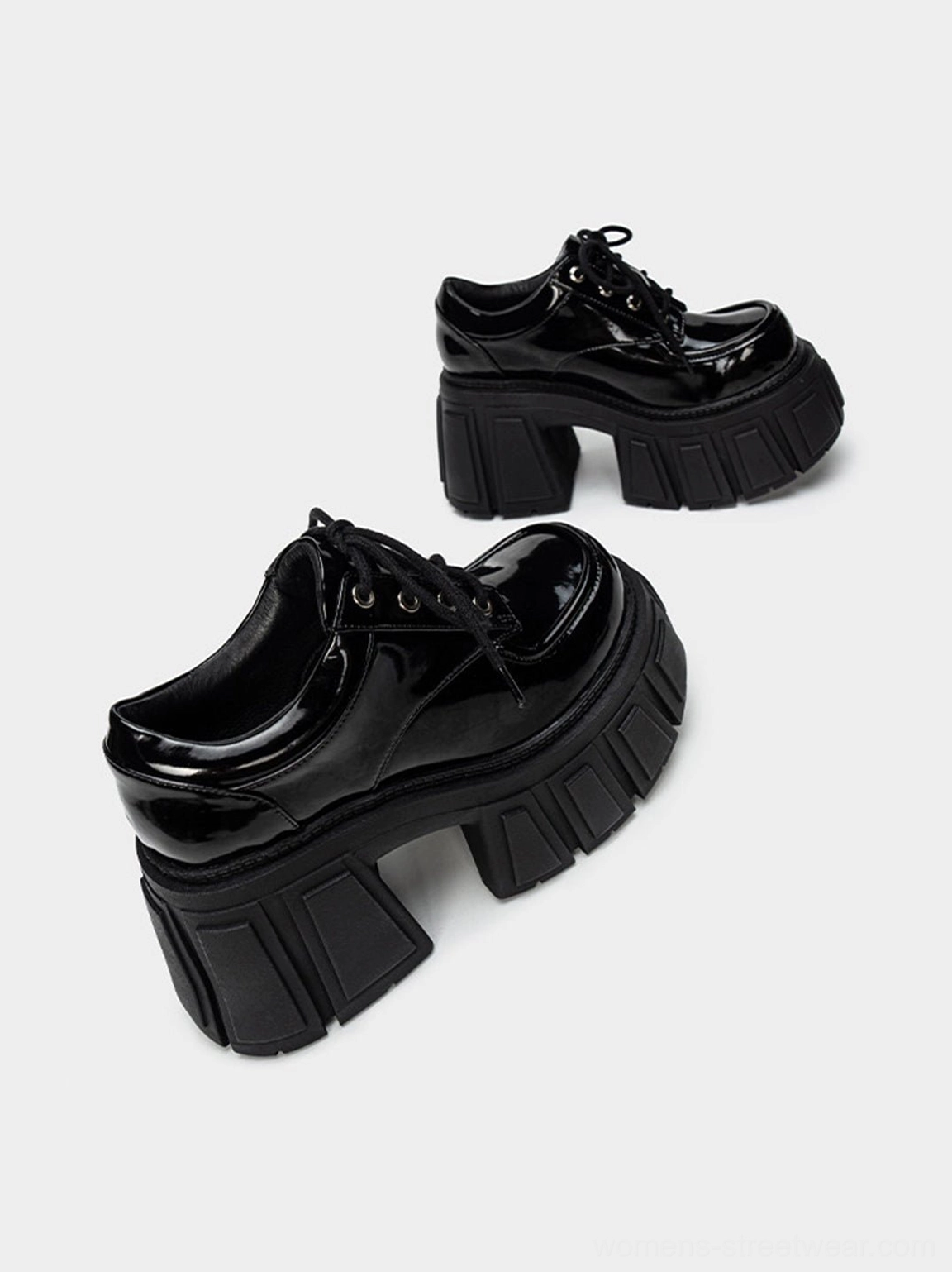 Chunky black patent platform heels with classic derby styling, rounded toe, metal eyelets, and textured outsole