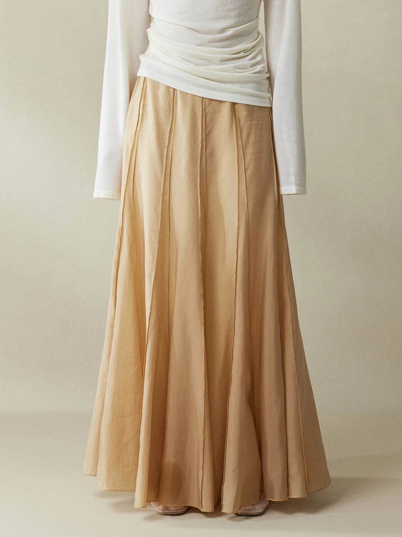 Cinnamon Brown paneled cupro fishtail maxi skirt photographed from a low front side angle with lightweight silky drape and vertical stitching