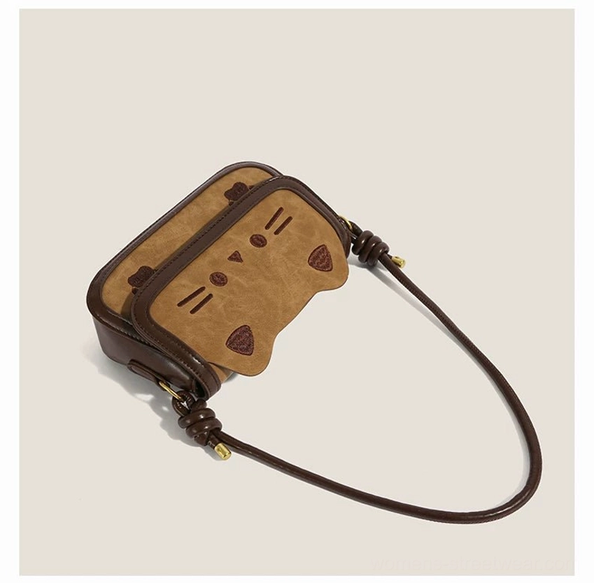 Lay flat view of cinnamon kitty convertible bag displaying full detachable brown crossbody strap and embroidered cat flap