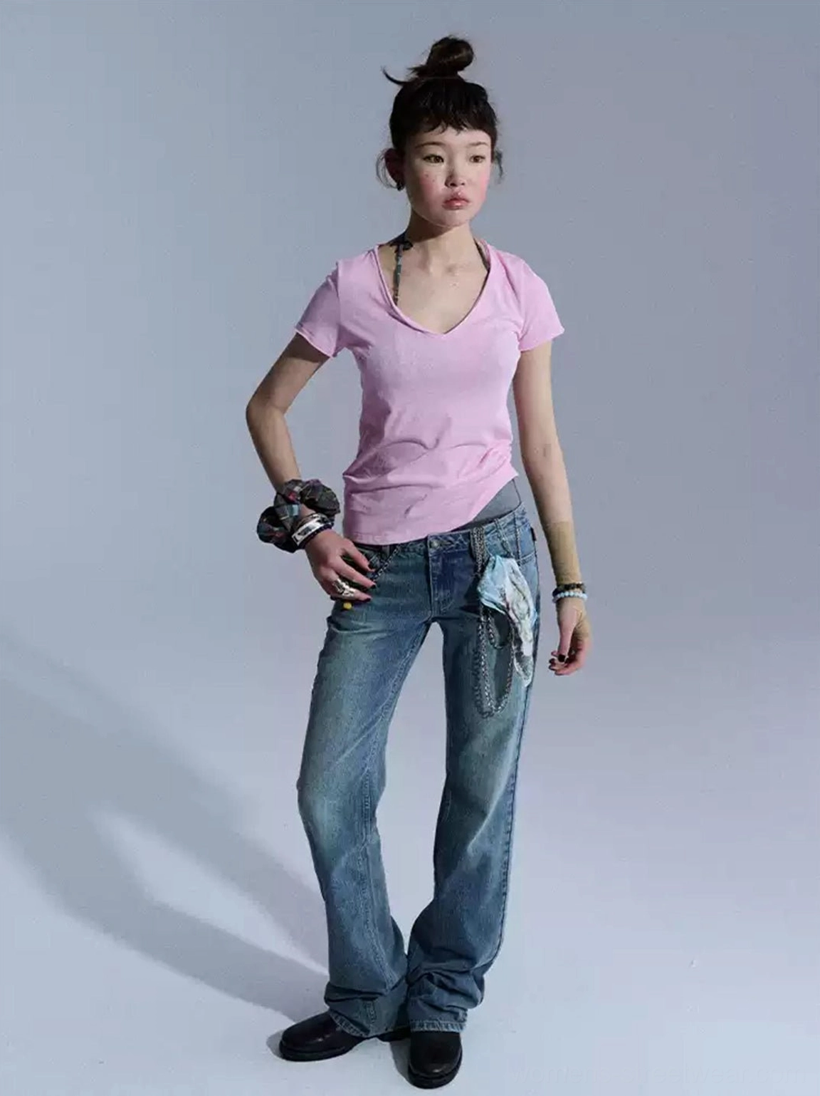 Front three-quarter view of classic blue low-rise flare jeans with waist chain and printed cloth accents styled with leather shoes