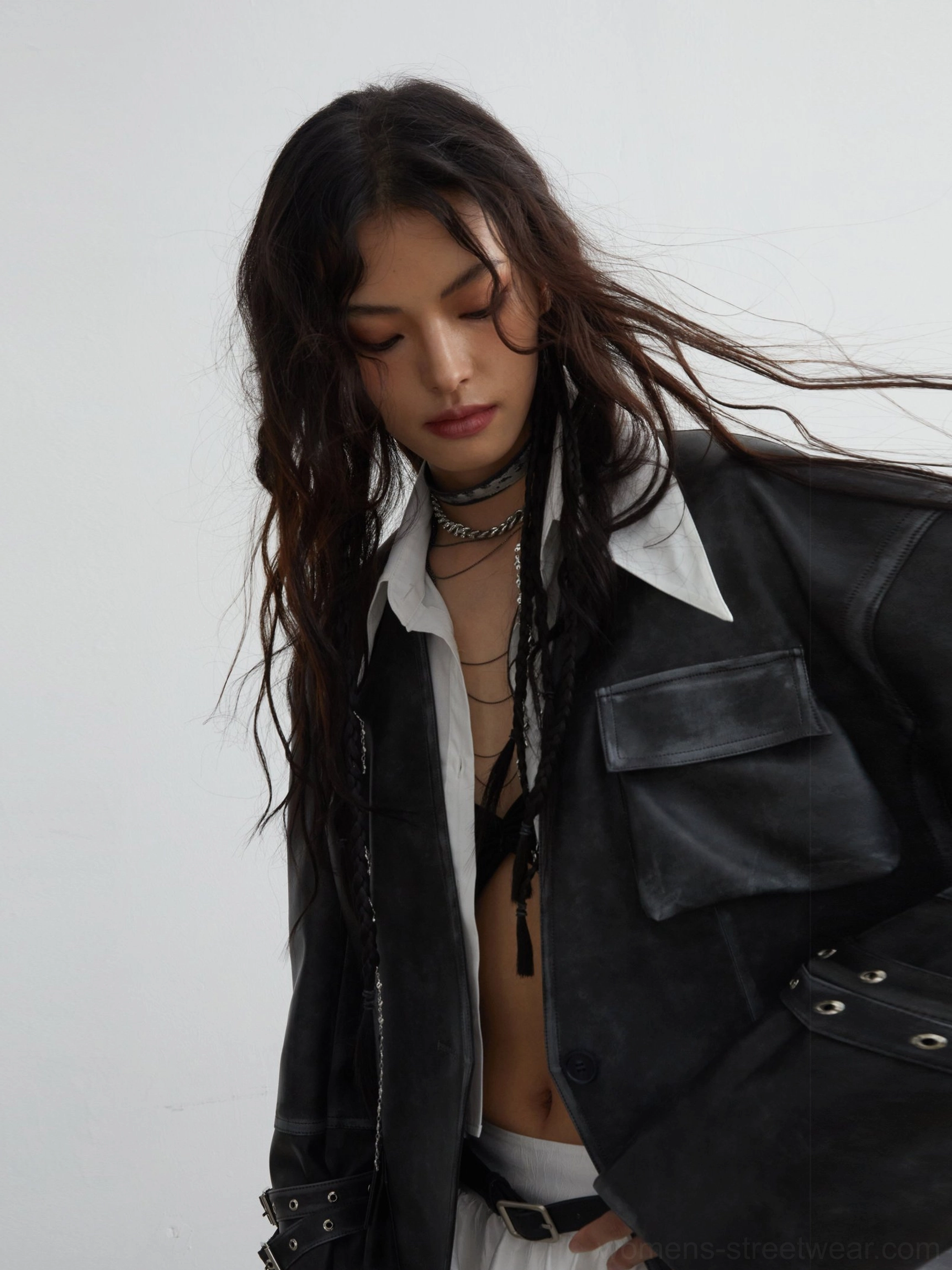 Close-up view of distressed PU leather jacket details showing textured finish, chest flap pockets, buckle cuff straps, and layered jewelry