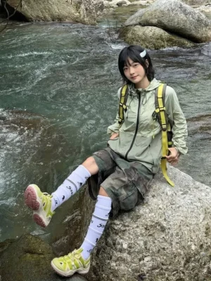 Women's outdoor creek trail hiking sandals with breathable mesh upper and chunky pink rubber outsole worn on a riverside rock