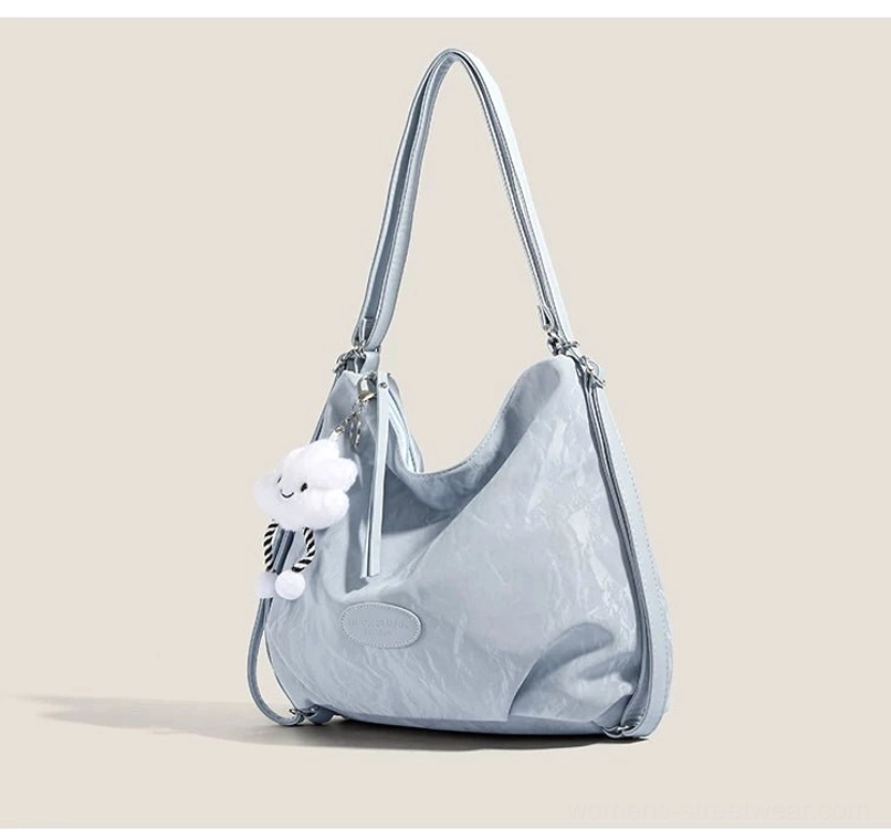 Light blue crinkle convertible hobo shoulder bag with cloud plush charm and adjustable silver strap side three quarter view