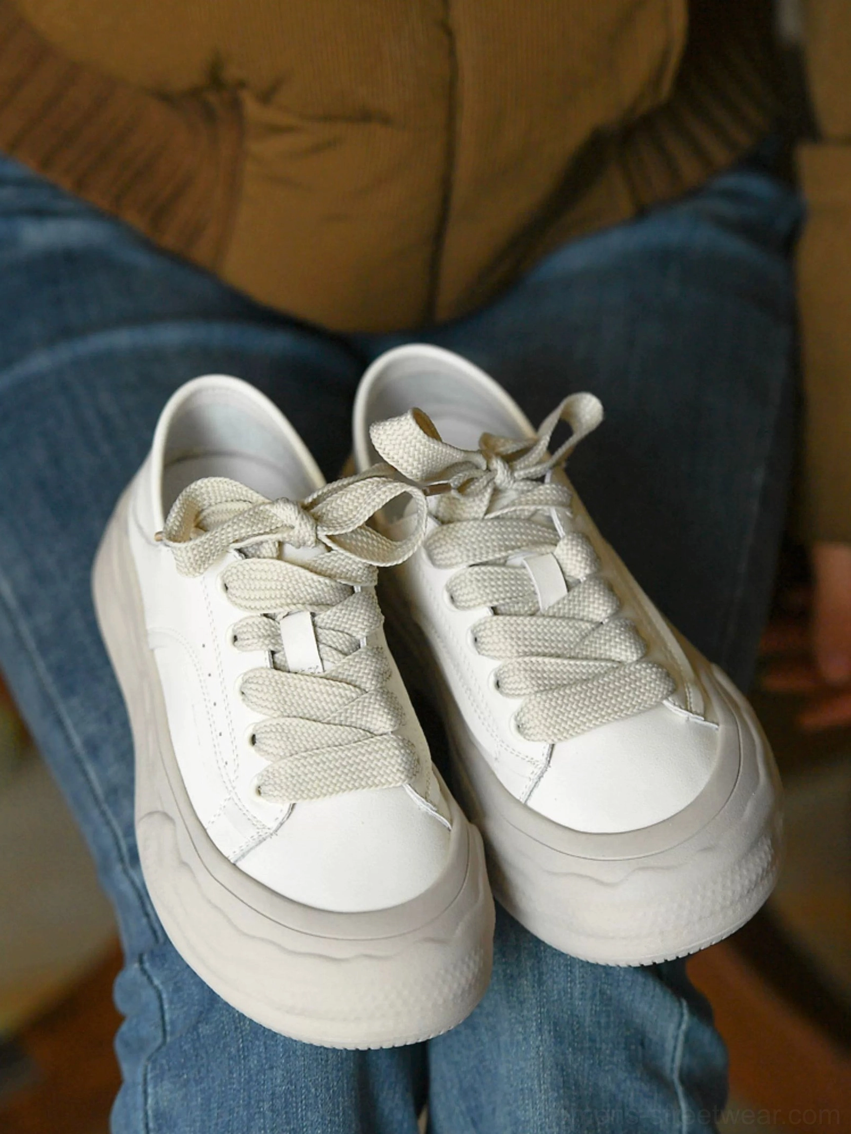 Front flat lay of a pair of grayish white chunky lace-up platform sneakers with clean leather uppers and matte gray wave soles