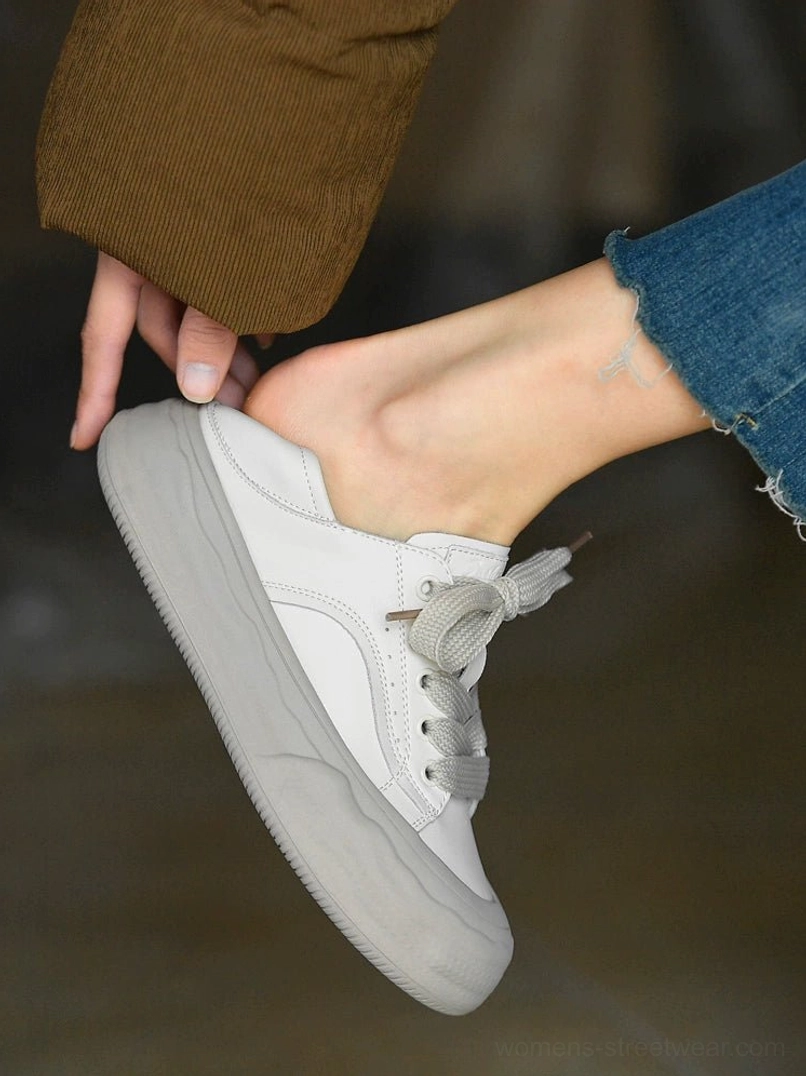 Side close-up of grayish white chunky platform sneakers worn with cropped denim jeans, showing the smooth leather upper and gradient gray rubber sole