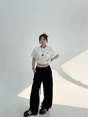 Black high-waist wide-leg cotton fleece streetwear sweatpants styled with a cropped white tee in a full-body front view