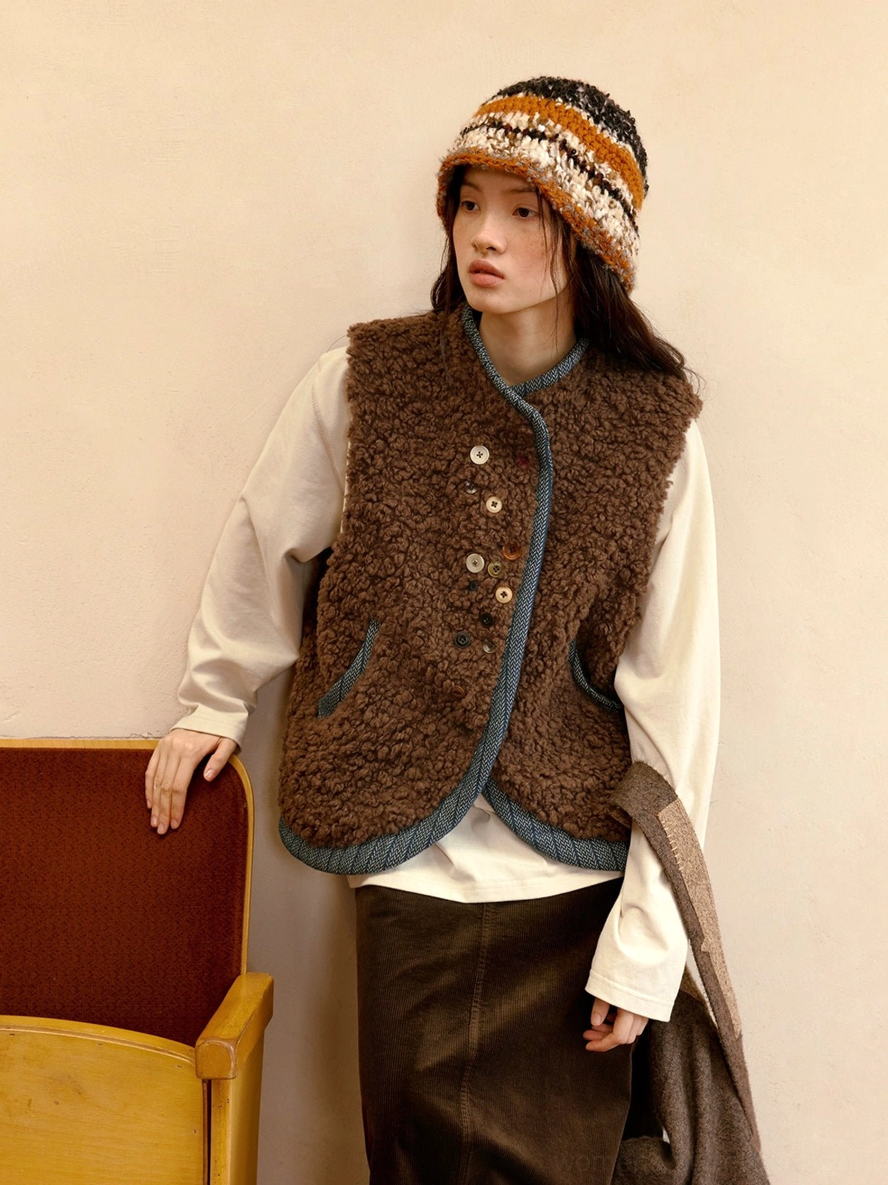 Cocoa brown reversible sherpa vest with blue contrast trim, plush fleece surface, and mismatched decorative buttons