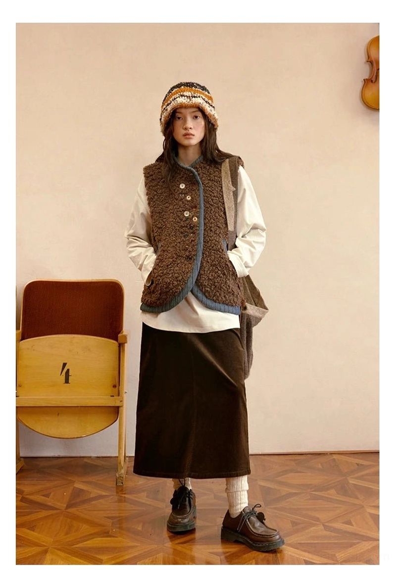 Cocoa brown sherpa vest front view styled with a midi skirt and loafers, showing blue edge trim and artistic button-front closure