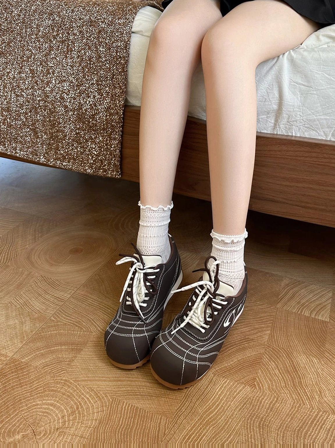 Coffee and beige retro low-profile trainers worn with frilled white socks in a casual indoor lifestyle setting