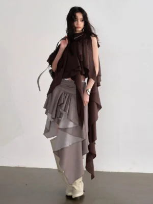 Coffee brown asymmetric cascade ruffle mock neck top styled with a gray layered skirt and off-white knee-high boots in a full body studio look