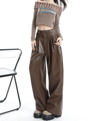 Front view of coffee brown pleated PU leather wide-leg pants with high waist glossy finish and platform shoe styling