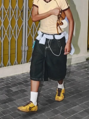 Yellow and brown retro suede star trainers worn with white crew socks, cropped top, and baggy shorts in an urban streetwear setting