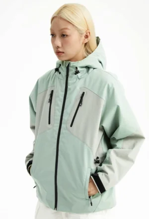 Mint green and light grey color block outdoor padded hooded jacket shown from a three-quarter front view with chest zip pockets and adjustable hood cords