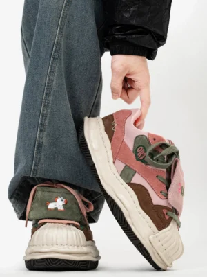 Side view of color block streetwear sneakers with brown pink and olive green suede-style panels, cartoon horse patch, and chunky cream sole