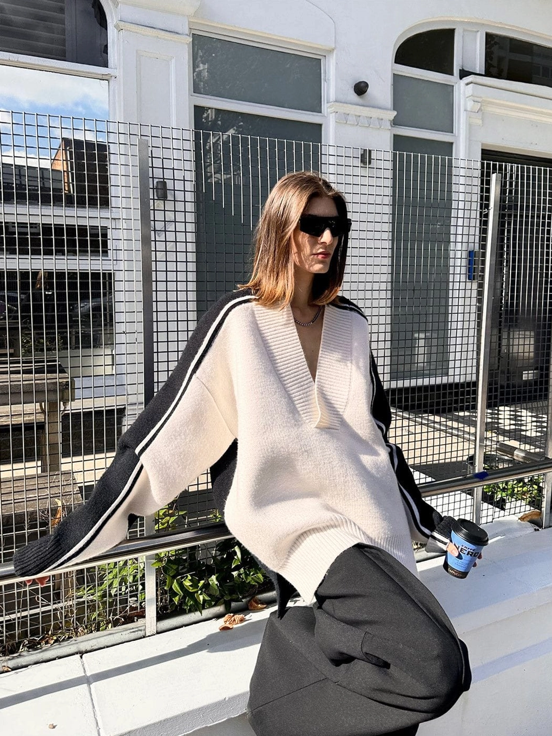 Three quarter view of color block V-neck racing stripe sweater styled with loose black trousers for Korean streetwear