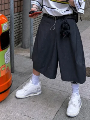 Colorblock basketball-inspired streetwear court sneakers styled with black baggy shorts, striped cropped top, and white crew socks on an urban sidewalk