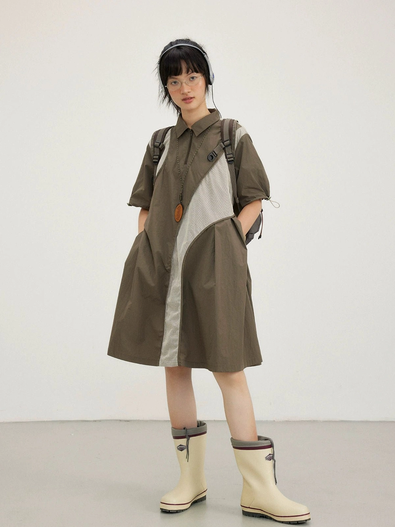 Oversized colorblock shirt dress with curved panels, shirt collar, relaxed short sleeves, glasses, headphones, and rain boots