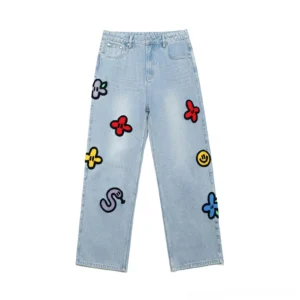 Light wash embroidered straight-leg jeans with colorful flower smiley face and snake chenille patches in a front flat lay view